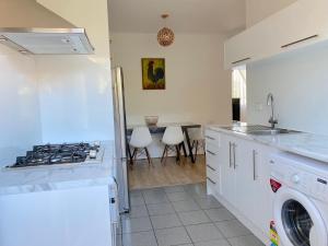 a white kitchen with a stove top oven next to a sink at Glenelg Holiday Apartments-The Broadway in Glenelg
