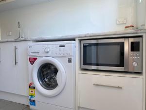a microwave and a washing machine in a kitchen at Glenelg Holiday Apartments-The Broadway in Glenelg