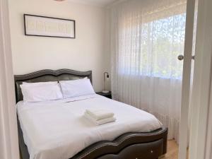 a bedroom with a bed with white sheets and a window at Glenelg Holiday Apartments-The Broadway in Glenelg