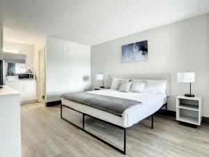 a white bedroom with a bed and a kitchen at Stayable Kissimmee West in Kissimmee