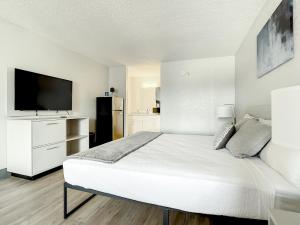 a white bedroom with a bed and a flat screen tv at Stayable Kissimmee West in Kissimmee
