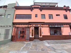 Uma casa cor-de-rosa com um portão à frente. em Mini depa en centro histórico de Pueblo Libre em Lima
