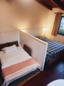 a small room with two beds in a room with a bedskirts at Palheiro do Avô in Santa Cruz