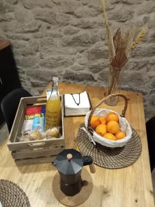 a table with a basket of oranges and a bottle of juice at A Casiña da Ponte in Padrón