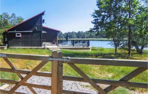 a barn with a fence in front of a lake at Amazing Home In Kalmar With House Sea View in Kalmar