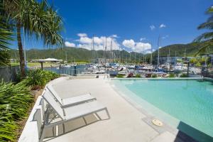 a swimming pool next to a marina with boats at Blue on Blue Studio Room 1322 in Nelly Bay