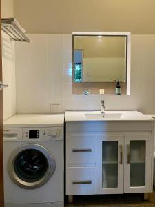 a bathroom with a washing machine and a sink at Tranquil Garden Apartment with living room in Wollongong