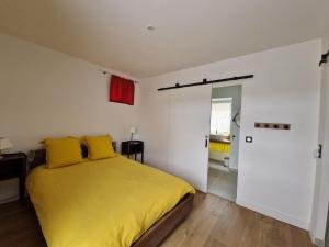 - une chambre avec un lit avec des draps jaunes et une porte dans l'établissement Finistère house 15 minutes from the bay of Morlaix, 