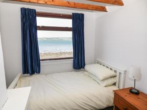 a bedroom with a bed and a window with the beach at Waters Edge in Stranraer