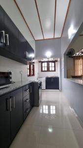 a large kitchen with black cabinets and a white floor at Ralph recedency in Kochchikade