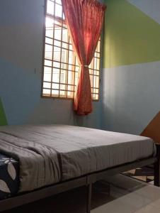 a bedroom with a bed and a window with a red curtain at Nafili homestay 3bd 2br in Kota Bharu