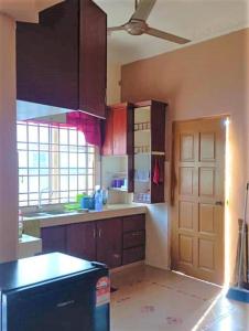 cocina con armarios marrones y nevera negra en Nafili homestay 3bd 2br en Kota Bharu