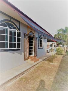 uma pequena casa branca com uma porta e um quintal em Nafili homestay 3bd 2br em Kota Bharu