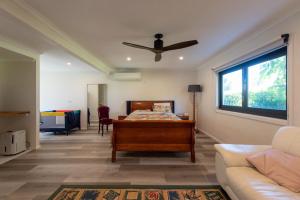 1 dormitorio con 1 cama y 1 sofá en Central Coast-Spacious House 5 minutes drive to beach en Tumbi Vmbi