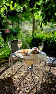 a table with a plate of food and two glasses of wine at Holly House Garden Studio in Moyhu