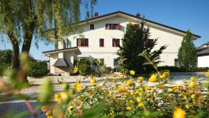 a white house with trees and flowers in the foreground at A Casa Di Paola in Chiarano