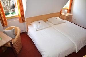 1 dormitorio con cama blanca, mesa y ventana en velcrea, en Willebadessen