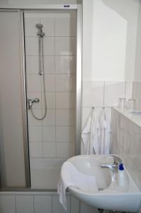 ein weißes Bad mit einem Waschbecken und einer Dusche in der Unterkunft velcrea in Willebadessen