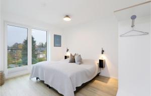 a white bedroom with a bed and a large window at Cozy Apartment In Lembruchdümmer See in Lembruch