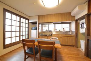 a kitchen with a wooden table and chairs and a kitchen with a counter at ファミリー&釣り好きに大人気の宿-松部漁港まで徒歩1分 in Katsuura