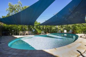 a swimming pool with two umbrellas on a patio at Magnetic North Apartment 1 in Arcadia