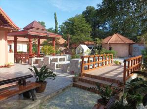 patio trasero con terraza de madera y banco de madera en Vimanmek Resort, en Yasothon