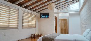 Rústic Quinta La Aurora في بانوس: غرفة نوم مع سرير وتلفزيون على الحائط
