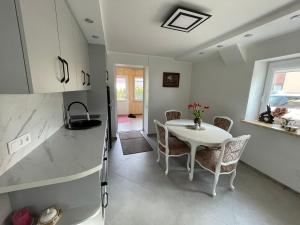 a kitchen with a white table and chairs in a room at Jaukus būstas Kintai in Kintai +10 photos