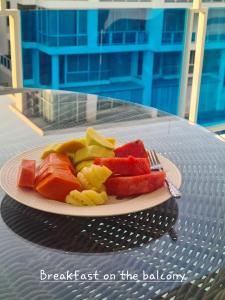 a plate of fruit on a table with a fork at Light, airy, east facing 2 bed/2 bath pool views in Hua Hin
