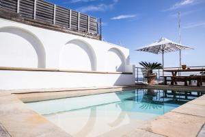 a swimming pool next to a white building with a table at Sea Castle Hotel Camps Bay in Cape Town