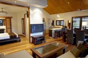 sala de estar con TV grande y cocina en Pure Magnetic Villa 6, en Nelly Bay