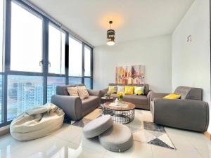 een woonkamer met banken, tafels en ramen bij KL Gateway 2B2B Cozy apartment in Kuala Lumpur