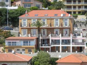 a large building with a palm tree in front of it at Hôtel La Flore in Villefranche-sur-Mer