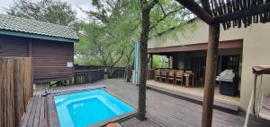 a swimming pool on a deck next to a house at Tranquillity Holiday Home in Marloth Park