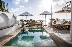 een zwembad op het dak van een gebouw met tafels en parasols bij Primi Seacastle in Kaapstad