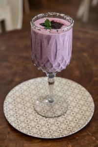 a purple drink in a glass on a white plate at Primi Seacastle in Cape Town