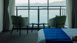 una camera d'albergo con un letto, due sedie e un tavolo di Yunoko Umi To Yuyake a Mizumata Altre 37 foto