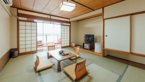 a living room with a table and chairs and a tv at Yunoko Umi To Yuyake in Mizumata