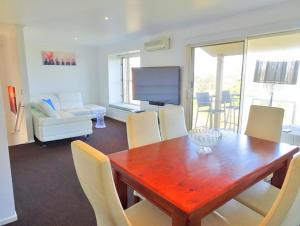 sala de estar con mesa de madera y sillas en Sea Views at Aqualuna 9 Solitary Islands Way 94, en Coffs Harbour