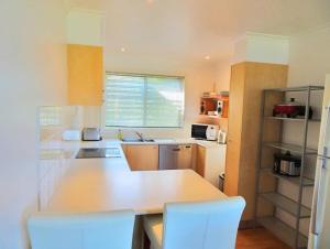 cocina con encimera blanca y sillas blancas en Sea Views at Aqualuna 9 Solitary Islands Way 94, en Coffs Harbour