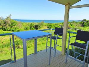 una mesa y dos sillas en una terraza con vistas al océano en Sea Views at Aqualuna 9 Solitary Islands Way 94, en Coffs Harbour