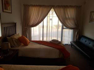 a bedroom with a bed and a large window at Karoo View Guesthouse Cradock in Cradock