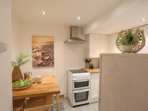 a kitchen with a refrigerator and a wooden table at Cottage in Pwllheli