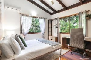 a bedroom with a bed and a desk and windows at Bindi Treehouse - Elevated Pole Home in Freshwater
