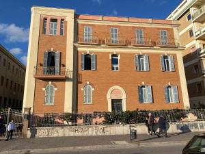 een groot bakstenen gebouw waar mensen voor lopen bij Alloggio in palazzina stile Liberty Fronte Mare in Nettuno
