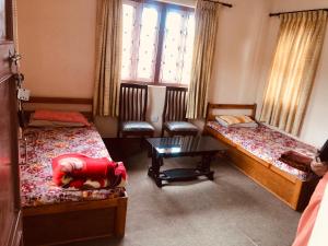 a room with two beds and a table and windows at Bungamati Community Homestay in Chapagaon