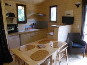 Il comprend une petite cuisine avec une table et des chaises en bois. dans l'établissement Le Chalet du Chloris, à Saint-Maxire