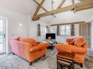 a living room with two chairs and a tv at Kings Barn in Weston under Lizard