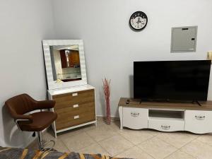 Rayyan Stays في دبي: غرفة معيشة مع تلفزيون بشاشة مسطحة وكرسي