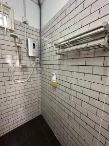 a white tiled bathroom with a shower and a soap dispenser at IBAI COTTAGE KUALA TERENGGANU (HOMESTAY) in Kuala Terengganu +45 photos